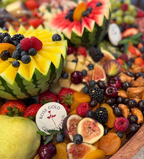 Colorful charcuterie board in Glendora, CA with carved watermelon bowls, figs, dried apricots, fresh fruit, and artisan cheeses by Rose Gold Charcuterie.