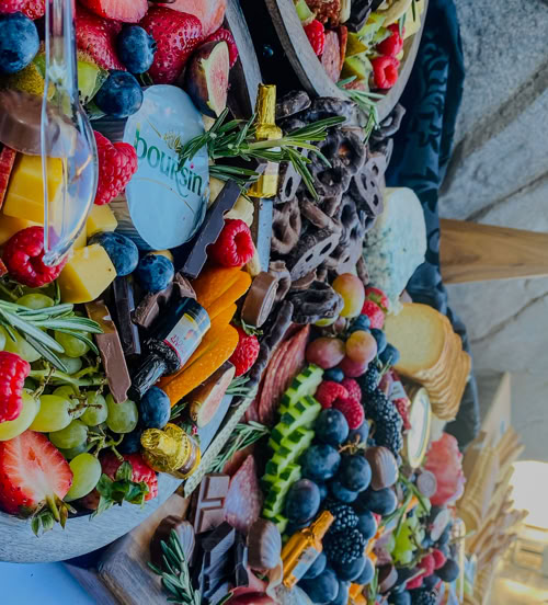 Colorful round charcuterie platters with Boursin cheese, berries, chocolate, fruit, and rosemary—ideal for special events and catering.