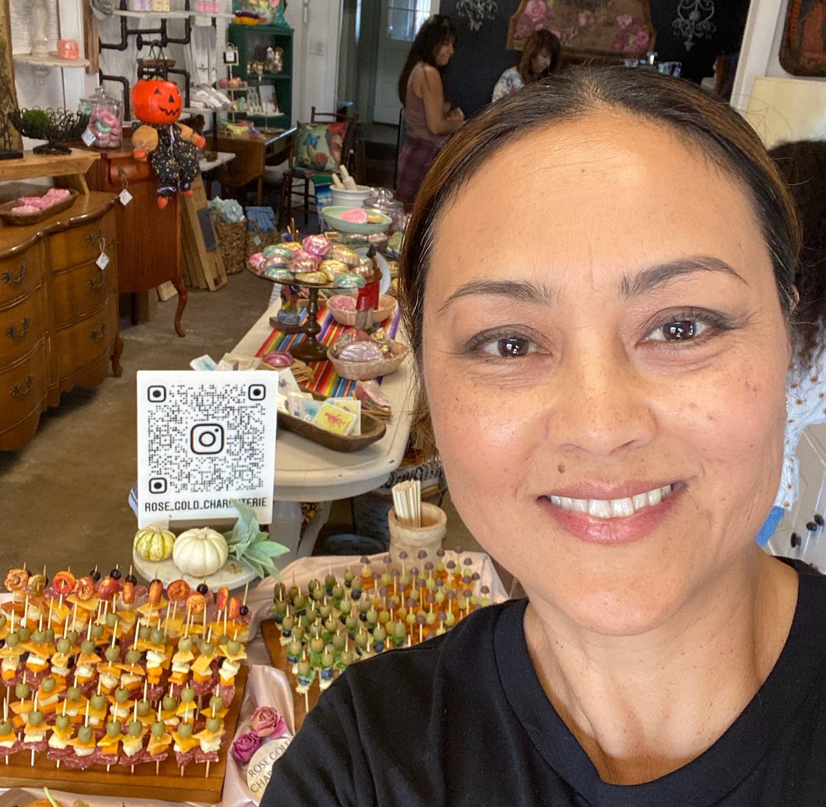 Owner of Rose Gold Charcuterie showcasing handcrafted charcuterie skewers, fruit trays, and event treats at a local boutique pop-up in Southern California.