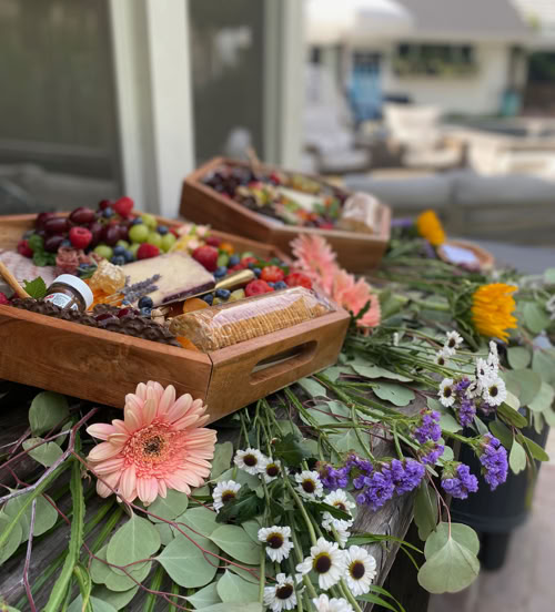 Wooden charcuterie boxes with cheeses, fruit, crackers, and floral styling for a San Dimas, CA event