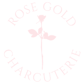 Rose Gold Charcuterie logo featuring a soft blush rose illustration centered on a mauve background. The text “ROSE GOLD CHARCUTERIE” circles around the rose in elegant white serif font, creating a refined and feminine look.