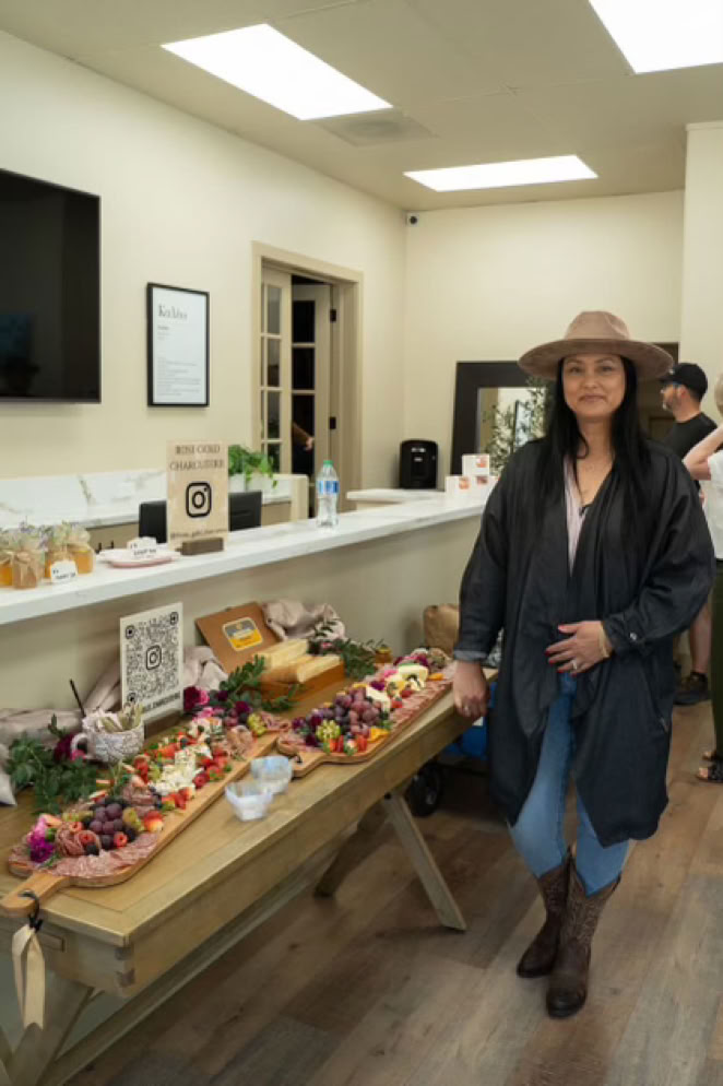 Owner of Rose Gold Charcuterie in Southern California standing beside a beautifully styled grazing table display at an indoor event.