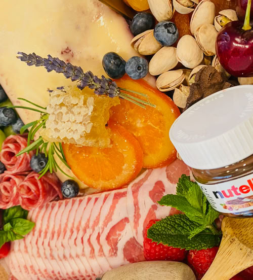 Artisan charcuterie with honeycomb, dried citrus, lavender, cheese, and fresh fruit including blueberries and cherries.