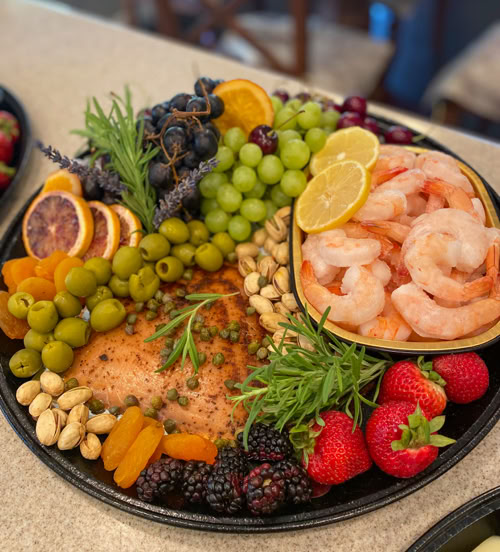 Custom seafood charcuterie board in San Dimas, CA with shrimp, smoked salmon, fresh fruit, olives, nuts, and herbs