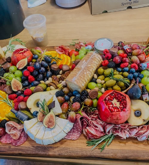 Oversized artisan charcuterie board featuring pomegranate, brie, cured meats, fruits, nuts, and crackers—perfect for events and parties in SoCal.